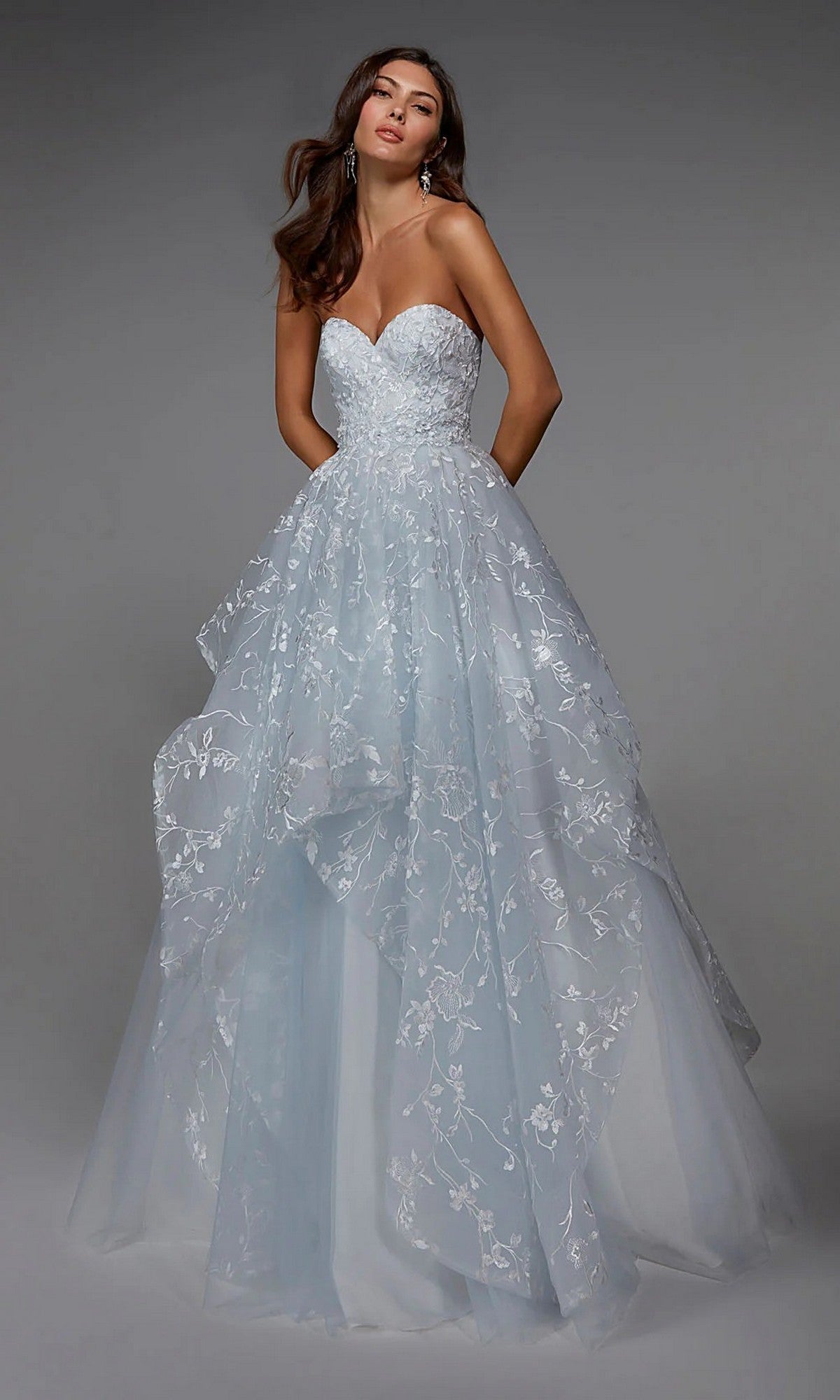 A woman wears the Alyce 7041 long formal dress, a strapless light blue gown with a sweetheart neckline, layered tulle skirt, and elegant white floral embroidery.